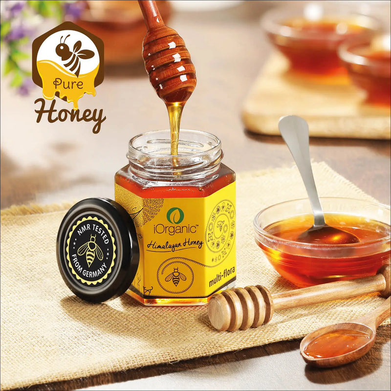 Jar of iOrganic Raw Multi-flora Honey with NMR tested seal, served with a wooden honey dipper, symbolizing the product's purity and high quality.