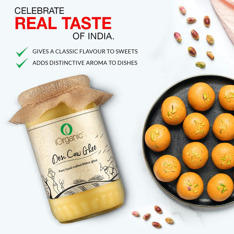iOrganic A2 Desi Cow Ghee with a traditional touch, placed next to Indian sweets garnished with pistachios, celebrating the 'REAL TASTE OF INDIA' by enhancing sweets with a classic flavour and a distinctive aroma.
